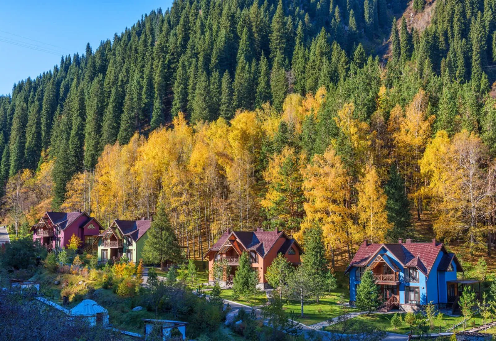 Colorful cottages set against golden autumn forest at Oi-Qaragai